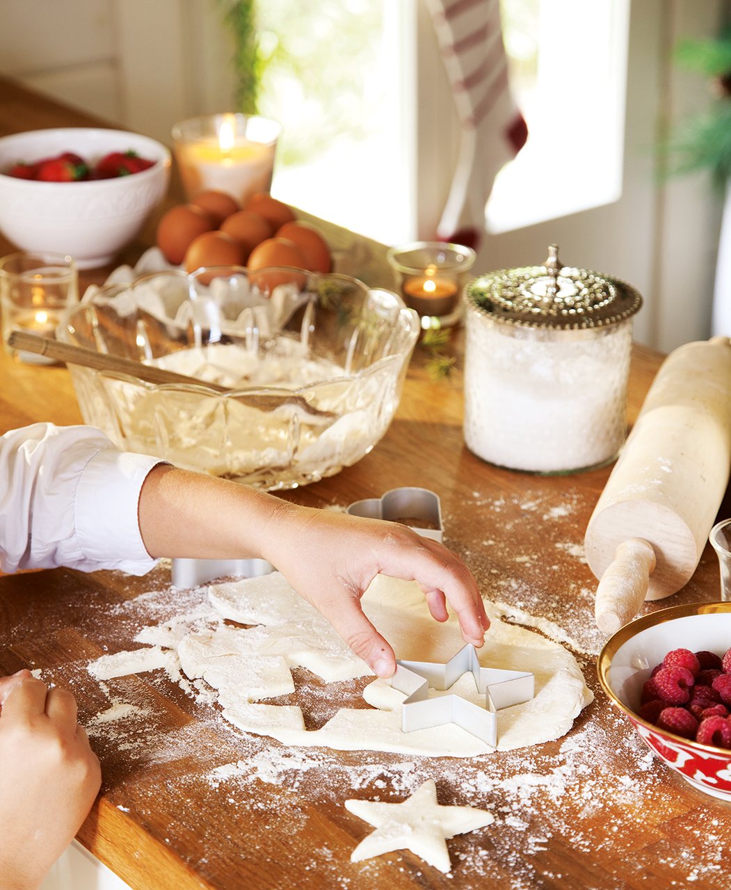 Detalle de mano con pasta y moldes para hacer galletas. Los cortapastas