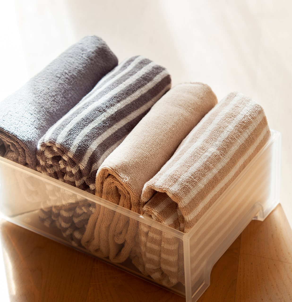 Detalle de toallas dobladas según el método de Marie Kondo. Toallas en beige y gris con diferentes estampados guardadas en una caja