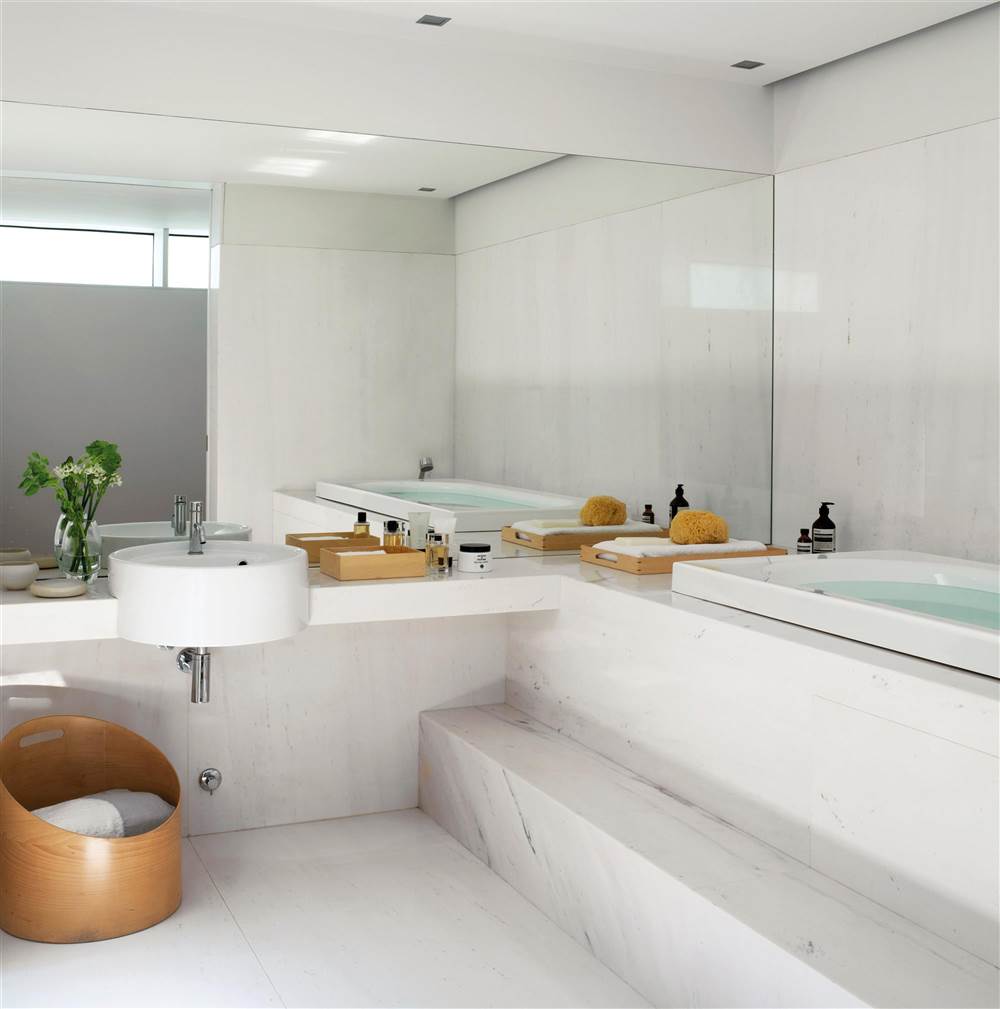 Baño revestido de mármol gris y blanco, con cesta de diseño en madera y gran espejo de lado a lado_240806