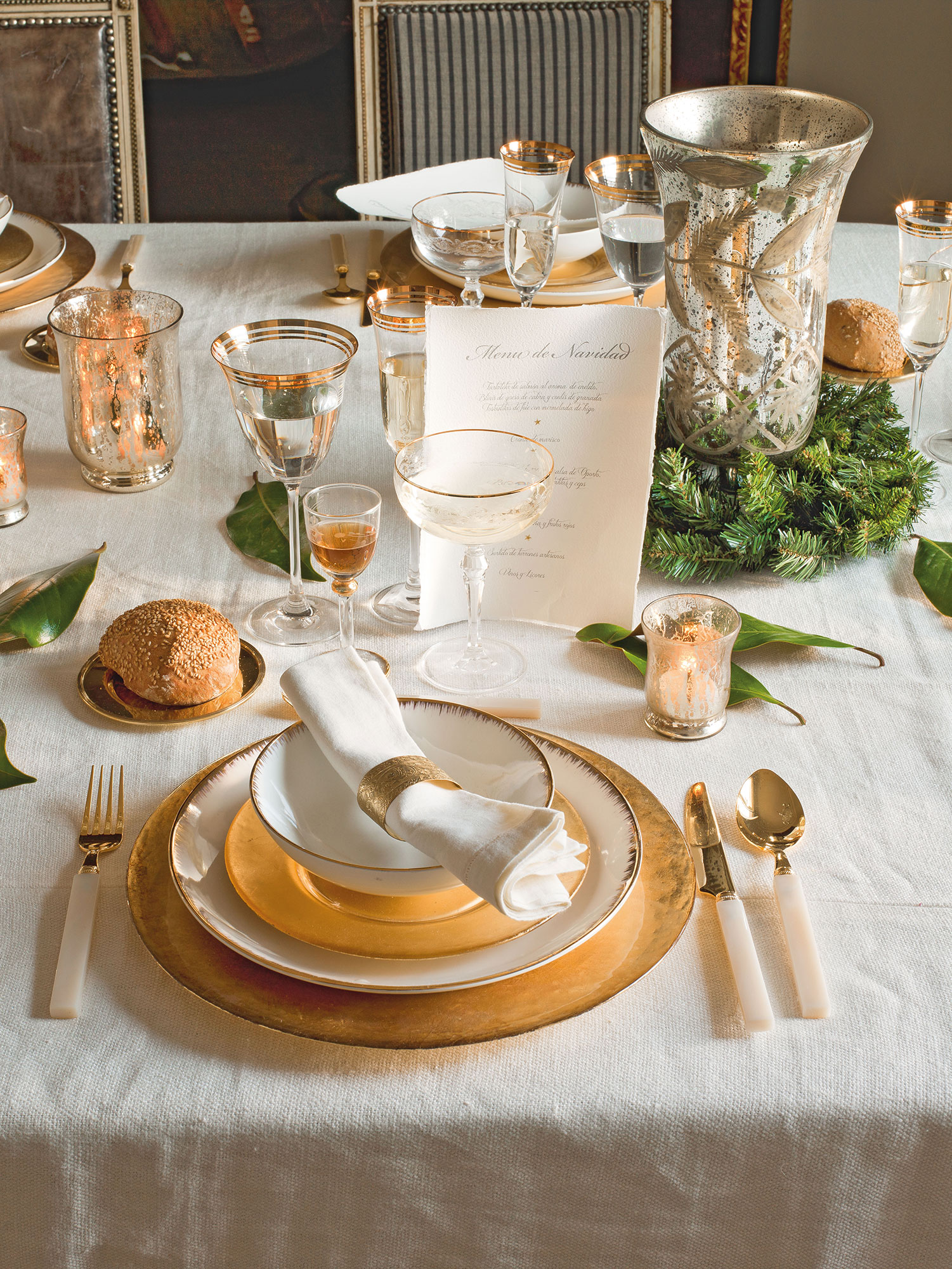 Detalle de mesa de comedor vestida en blanco y dorado para comida de Navidad 