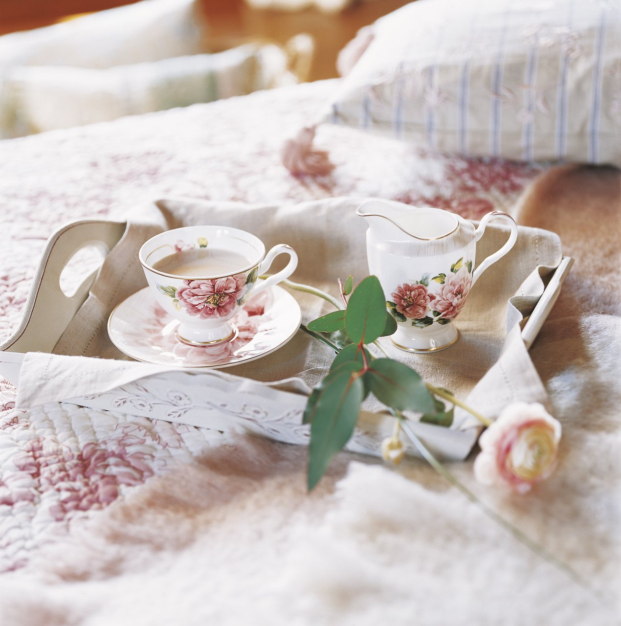 Juego de té floral en una bandeja sobre la cama