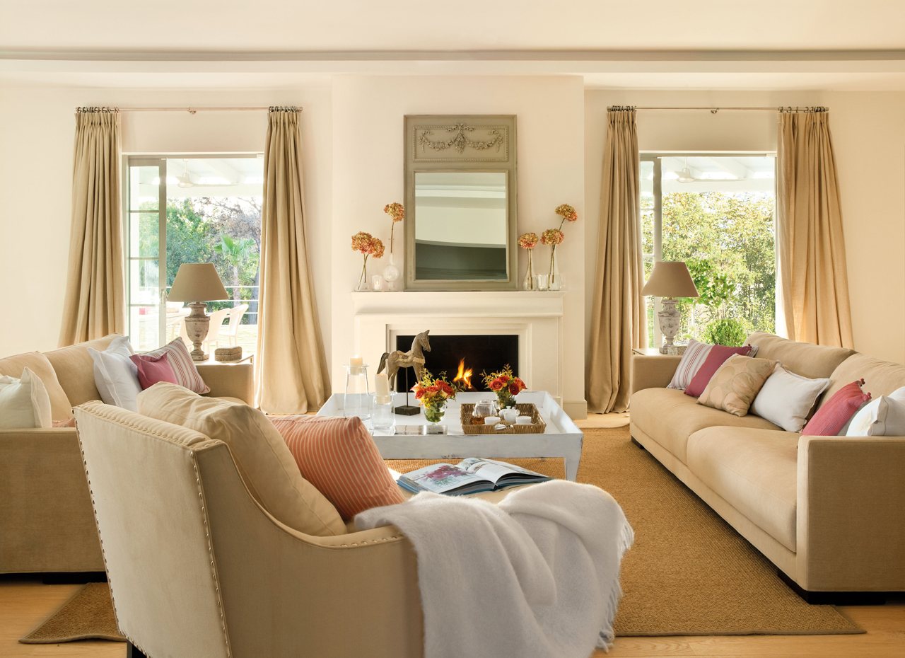 Salón de estilo clásico con chimenea, sofás y butaca en color beige