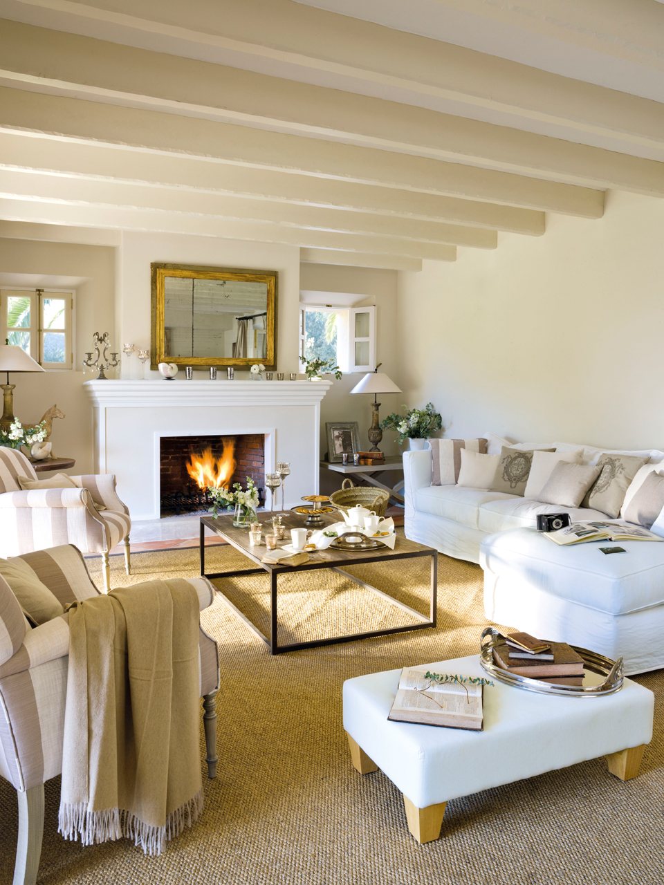 Salón de estilo provenzal con chimenea y sofá blanco con chaise longue