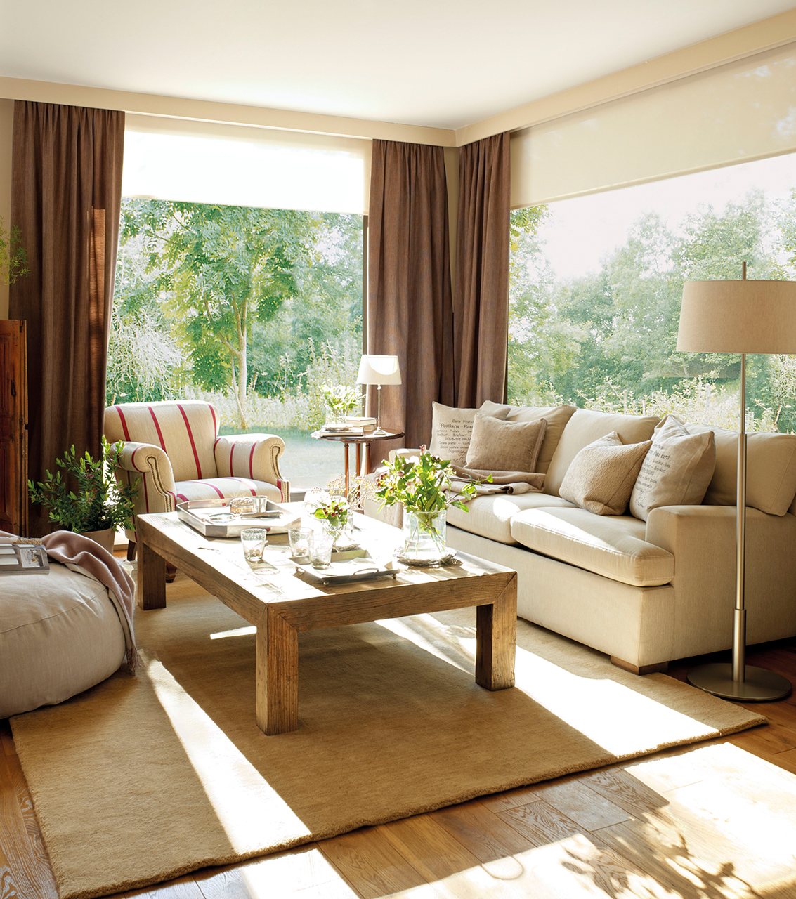 Salón con sofá beige, butaca de rayas y mesa de centro de madera.  