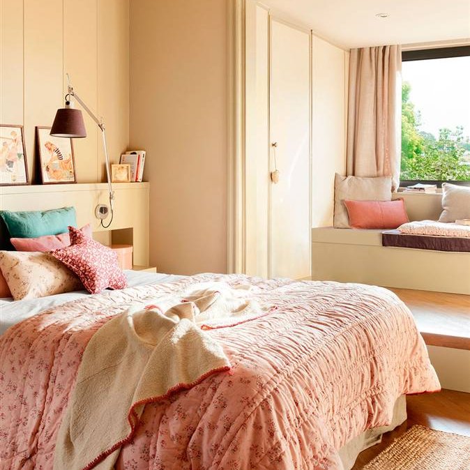 Dormitorio en tonos beig y textiles en rosa con escalón y banco bajo la ventana