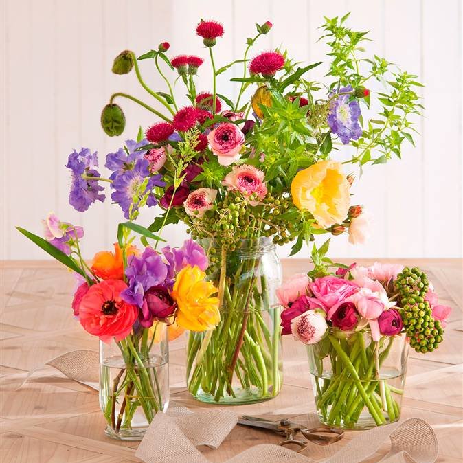 Ramos de flores de colores en amarillo, rojo, lila y rosa en jarrones de cristal