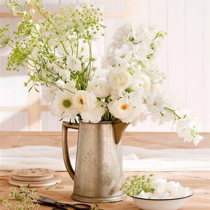 Romántico ramo de flores blancas en jarra de metal