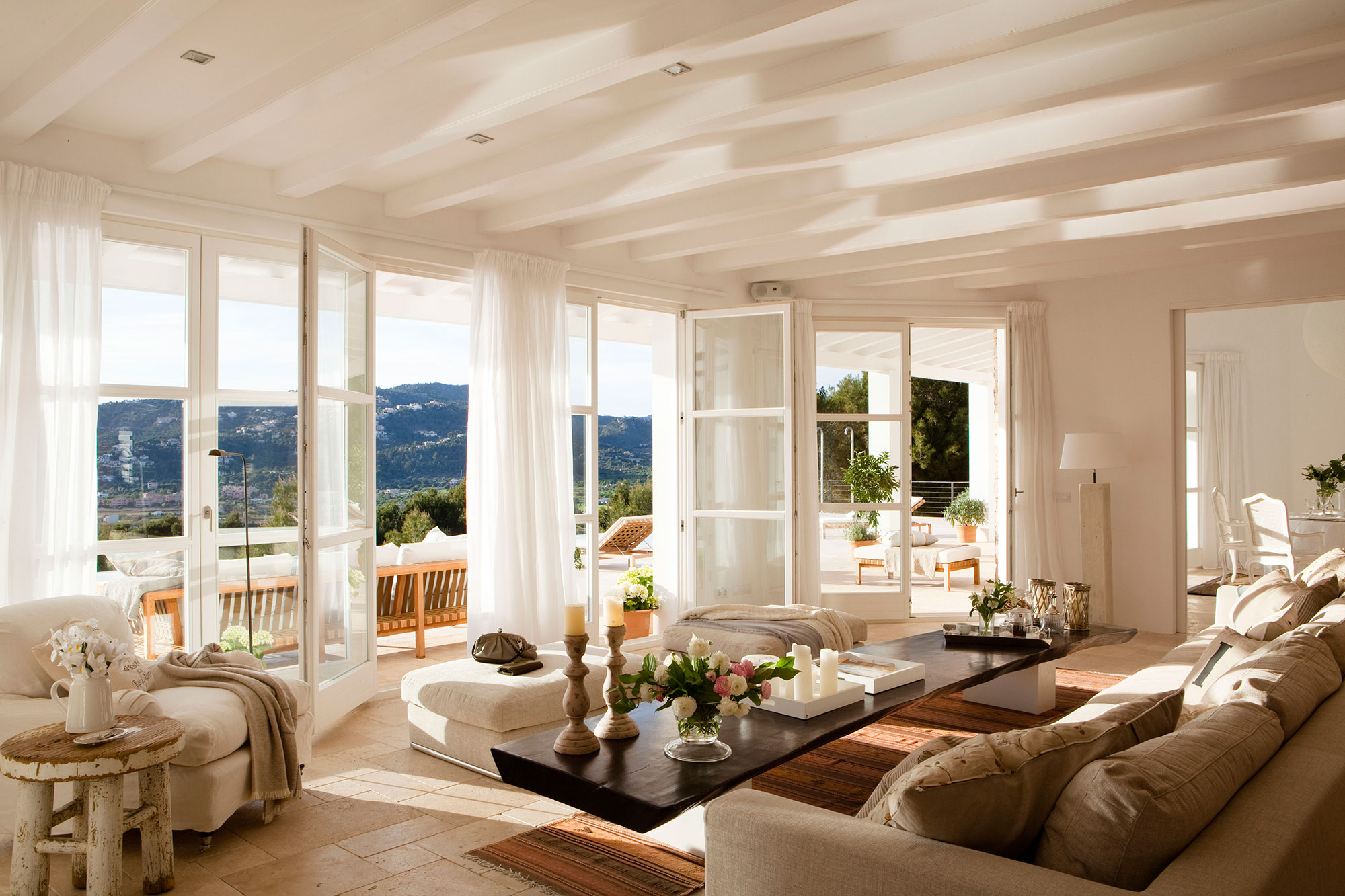 Salón blanco con una pared de ventanas con vistas a las montañas
