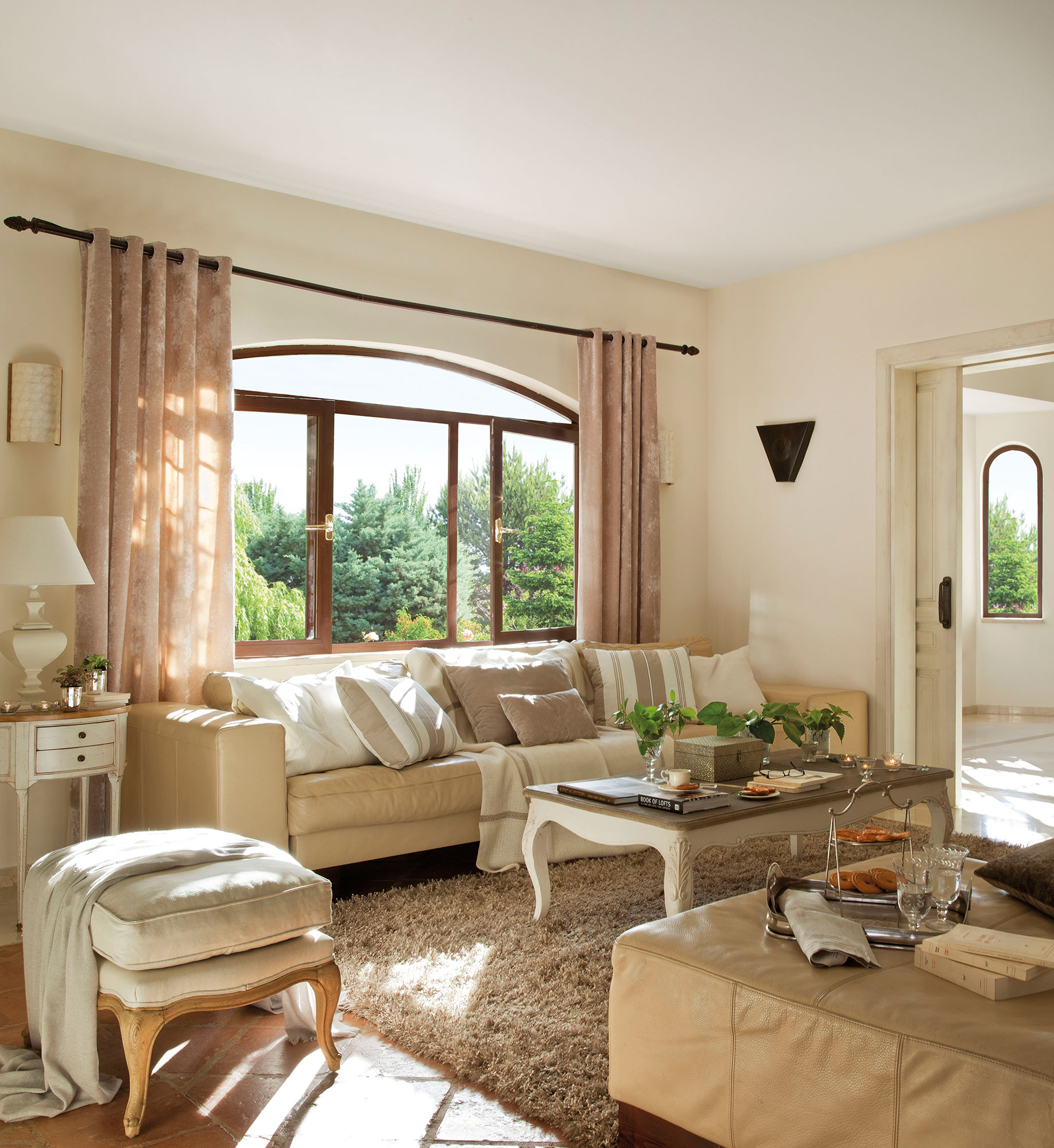 Salón clásico con sofás beige y mesa de centro blanca. 