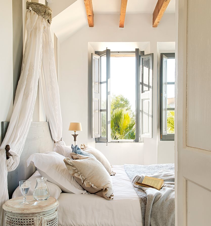 Dormitorio romático con corona de la que caen cortinas de lino