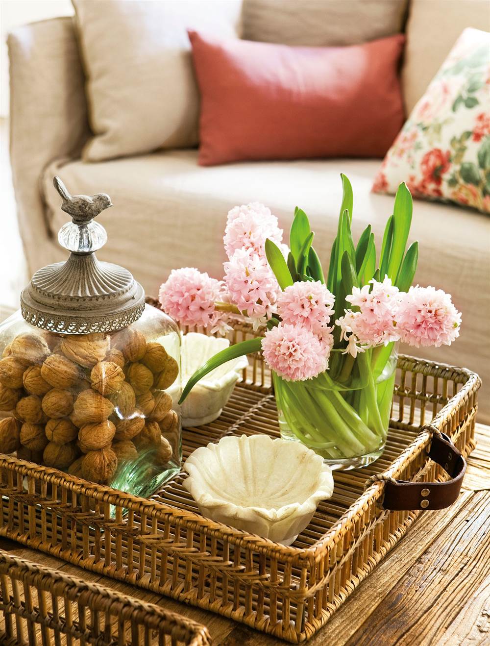 Detalle de mesa de centro con bandeja de fibras con objetos decorativos y flores