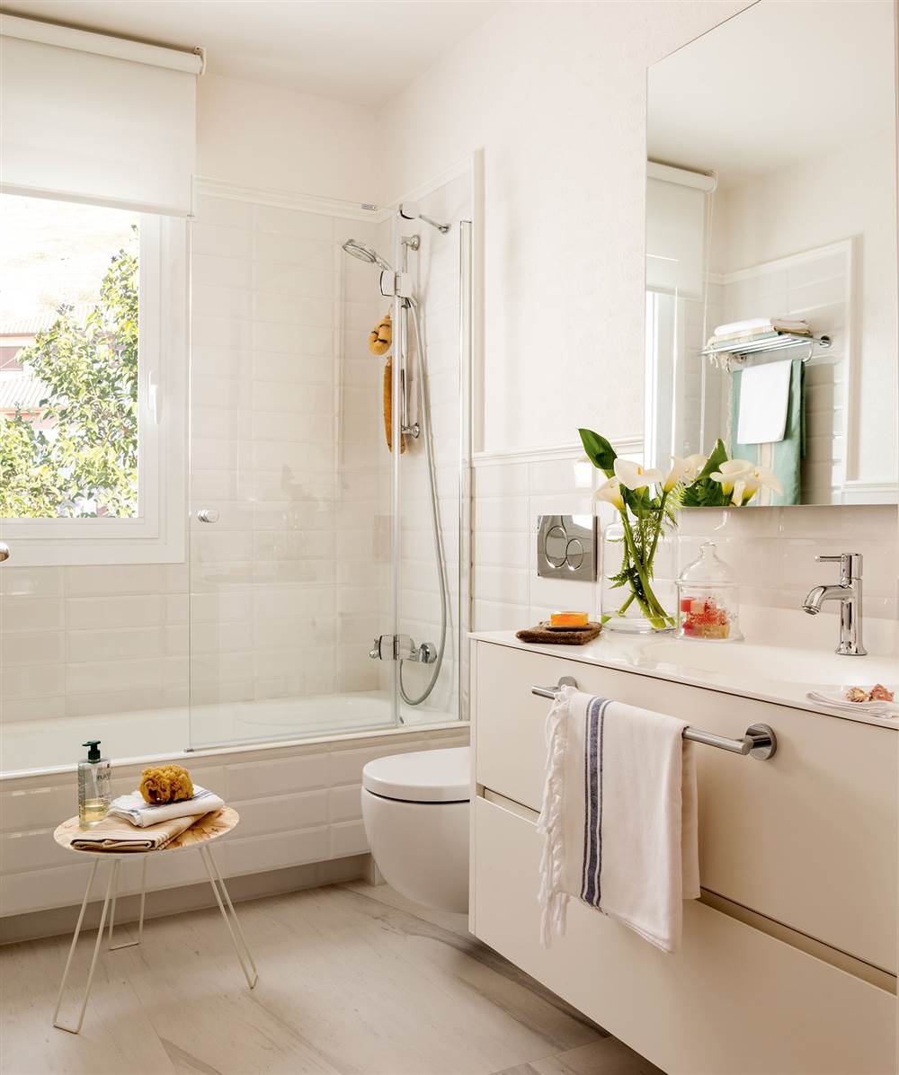 Baño en blanco con paredes alicatadas a media altura y pintadas y con bajolavabo y sanitario volados
