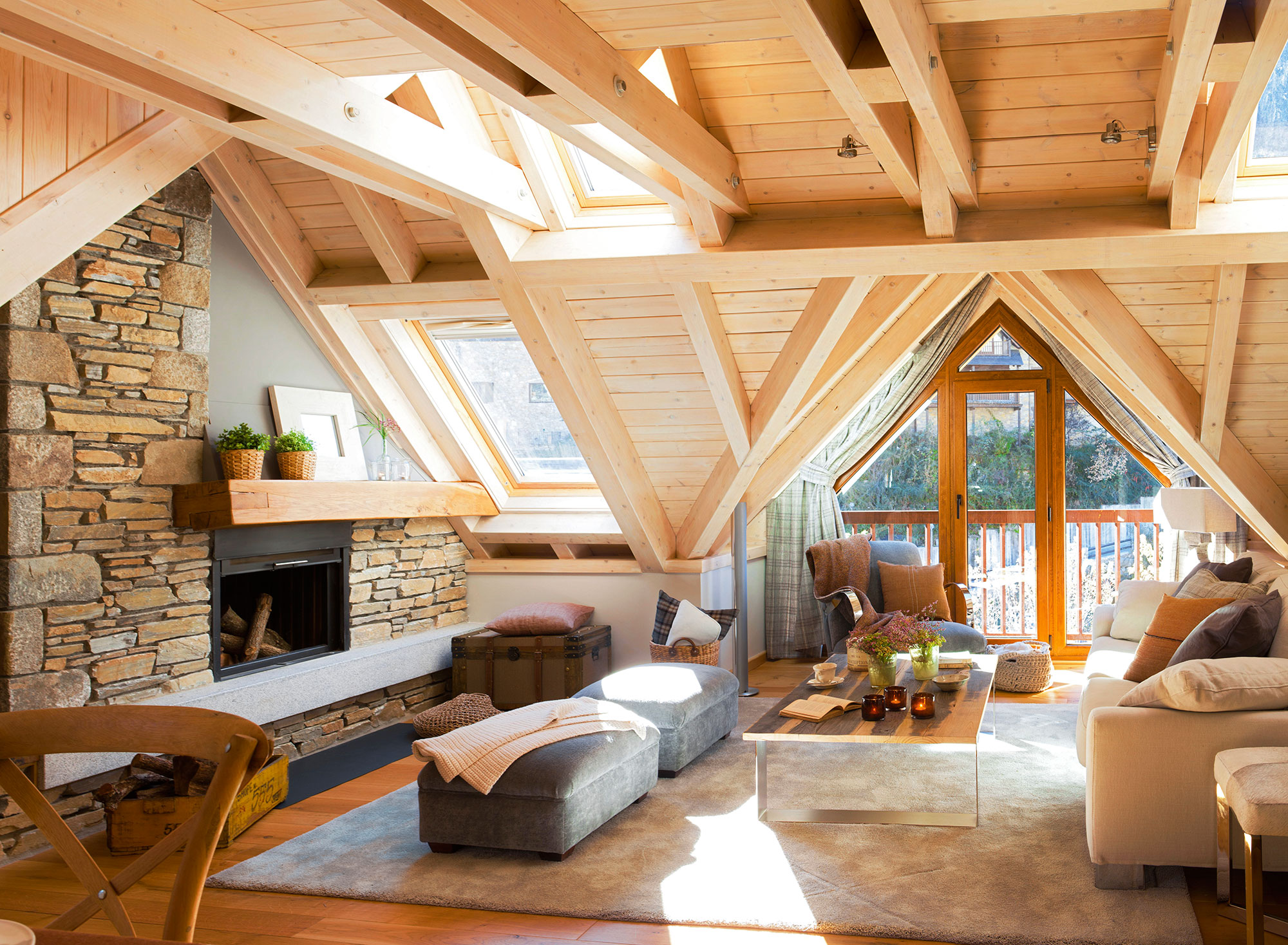 Salón rústico con chimenea de madera y techos abuhardillados de madera. 