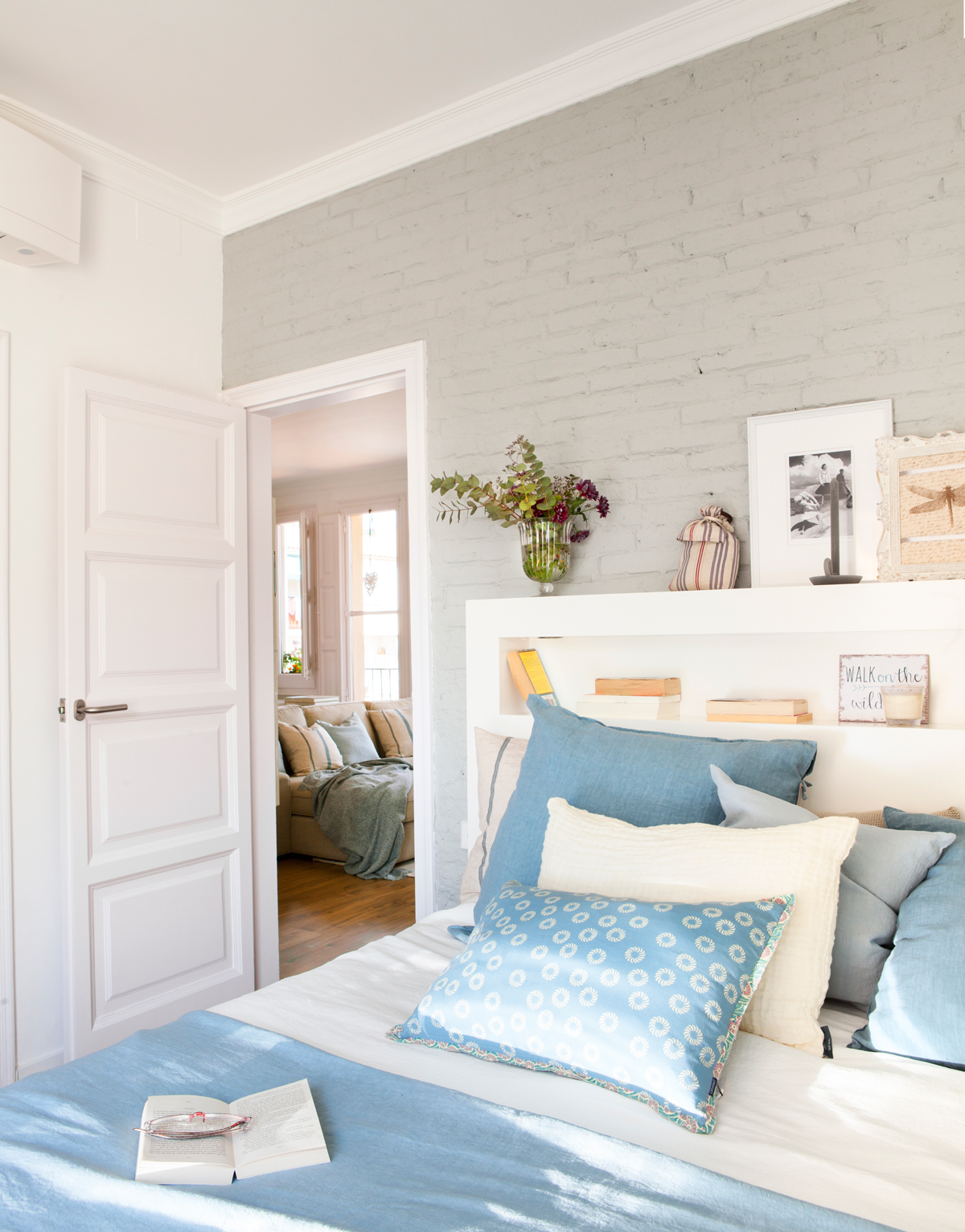 00429037. Dormitorio con pared de ladrillo en gris, ropa de cama en azul y blanco y cabecero con hueco de madera blanca 00429037