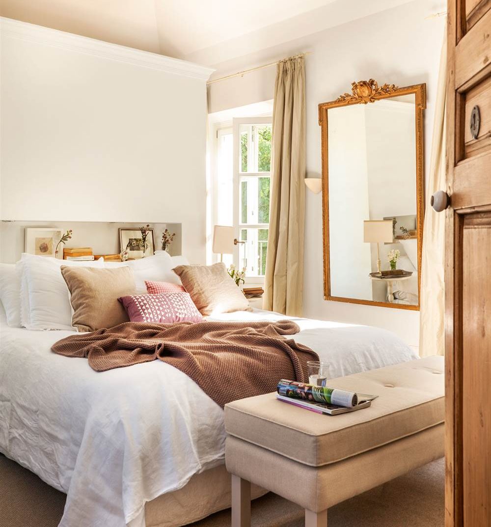 Dormitorio en blanco con cabecero murete y gran espejo con marco de pan de oro