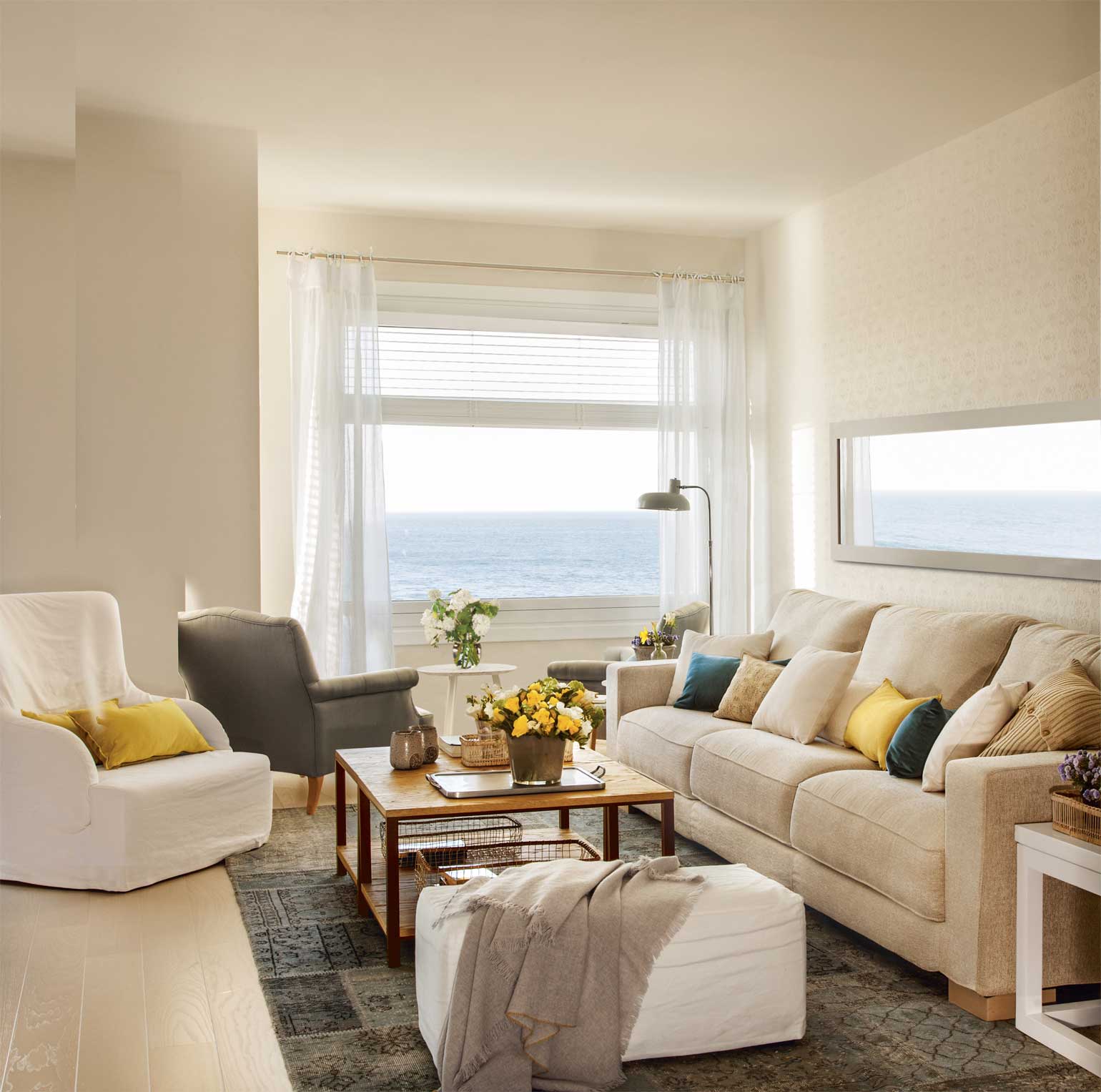 Salón con sofás blancos y vistas al mar. 