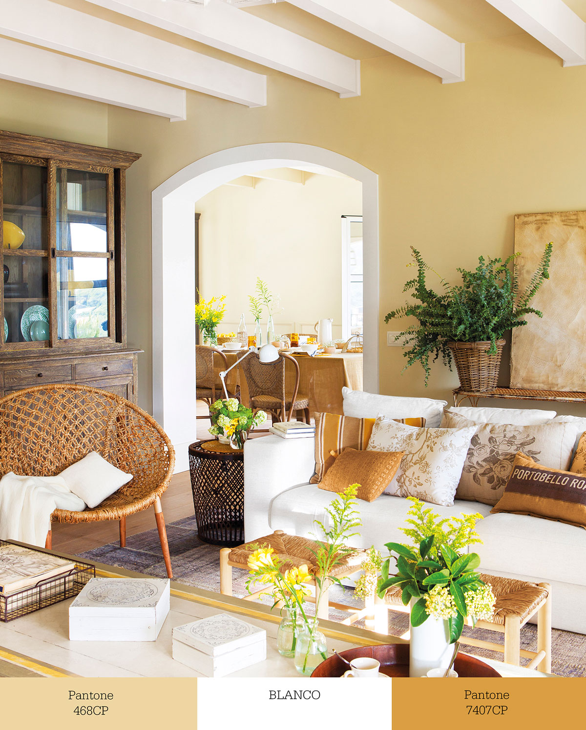 Salón con paredes beige, sofás blancos y cojines de color ocre. 