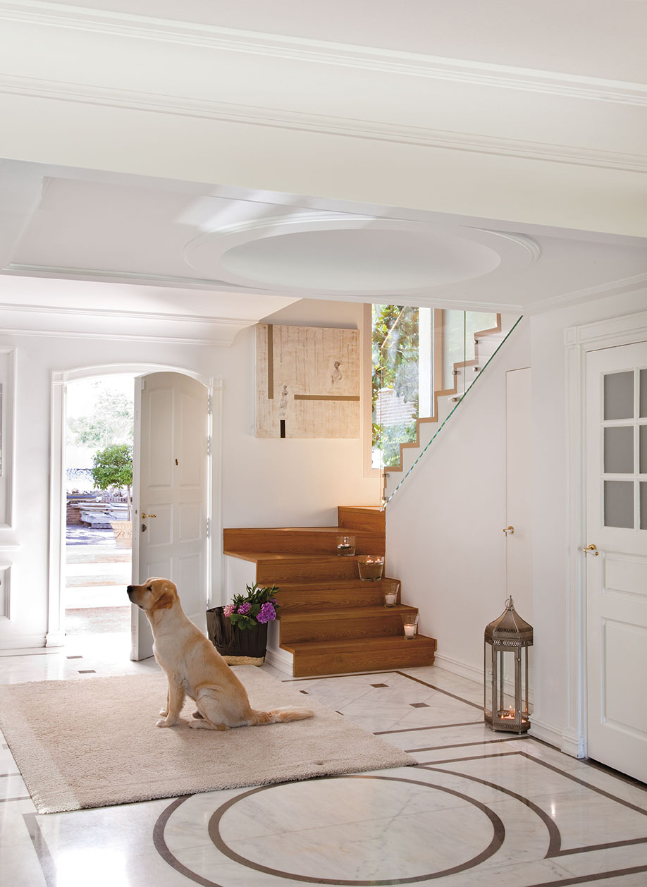 Recibidor clásico blanco con suelo de mármol y diseño circular en el suelo y techo con molduras