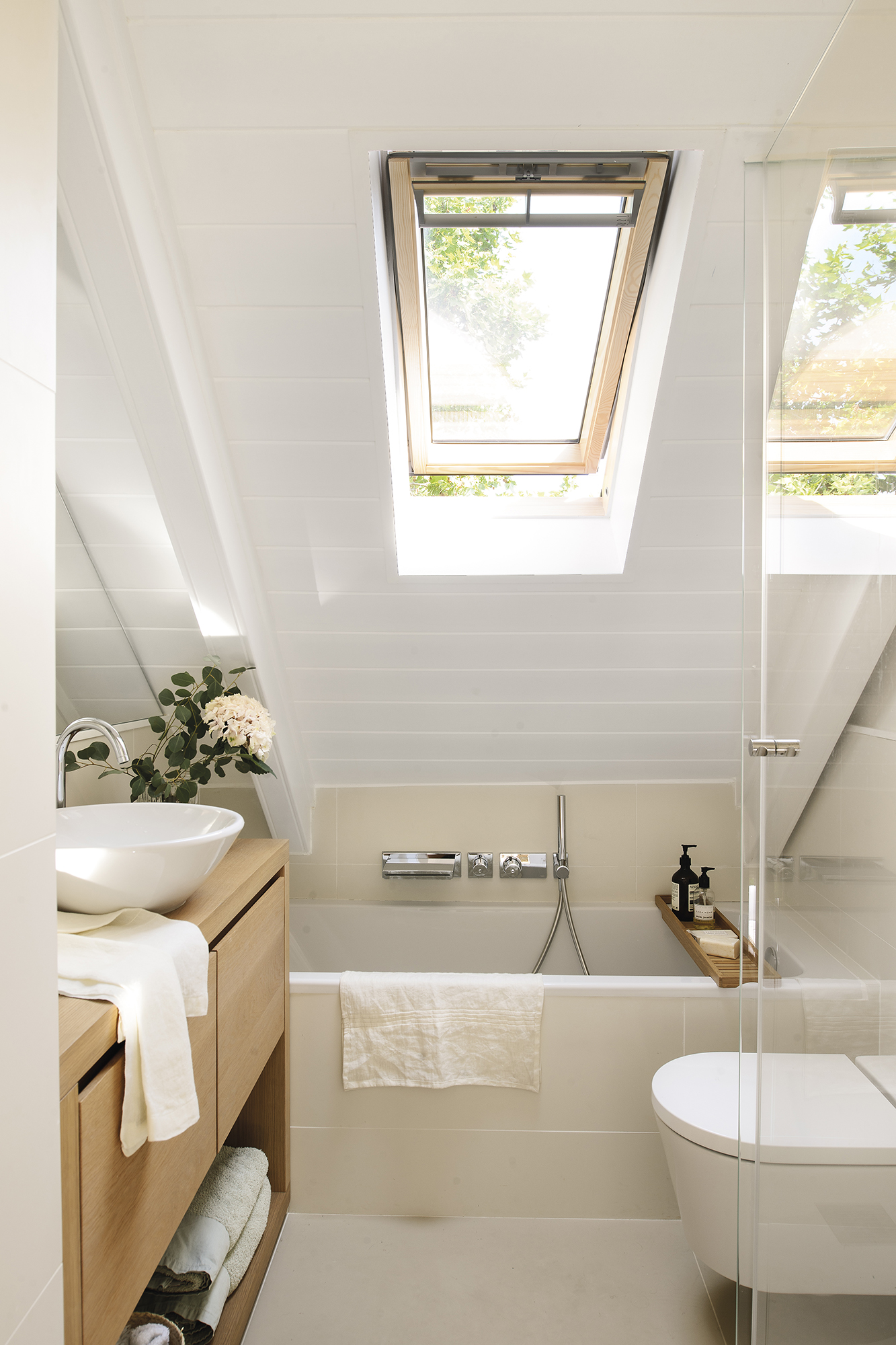 Baño con techo abuhardillado con ventana. 