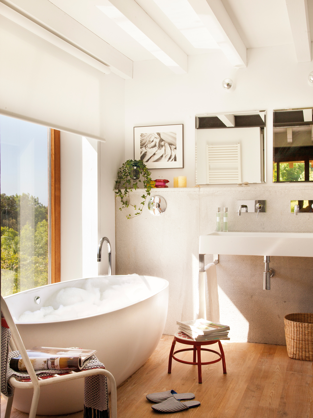 Baño moderno con bañera exenta decorado con suelo de madera. 