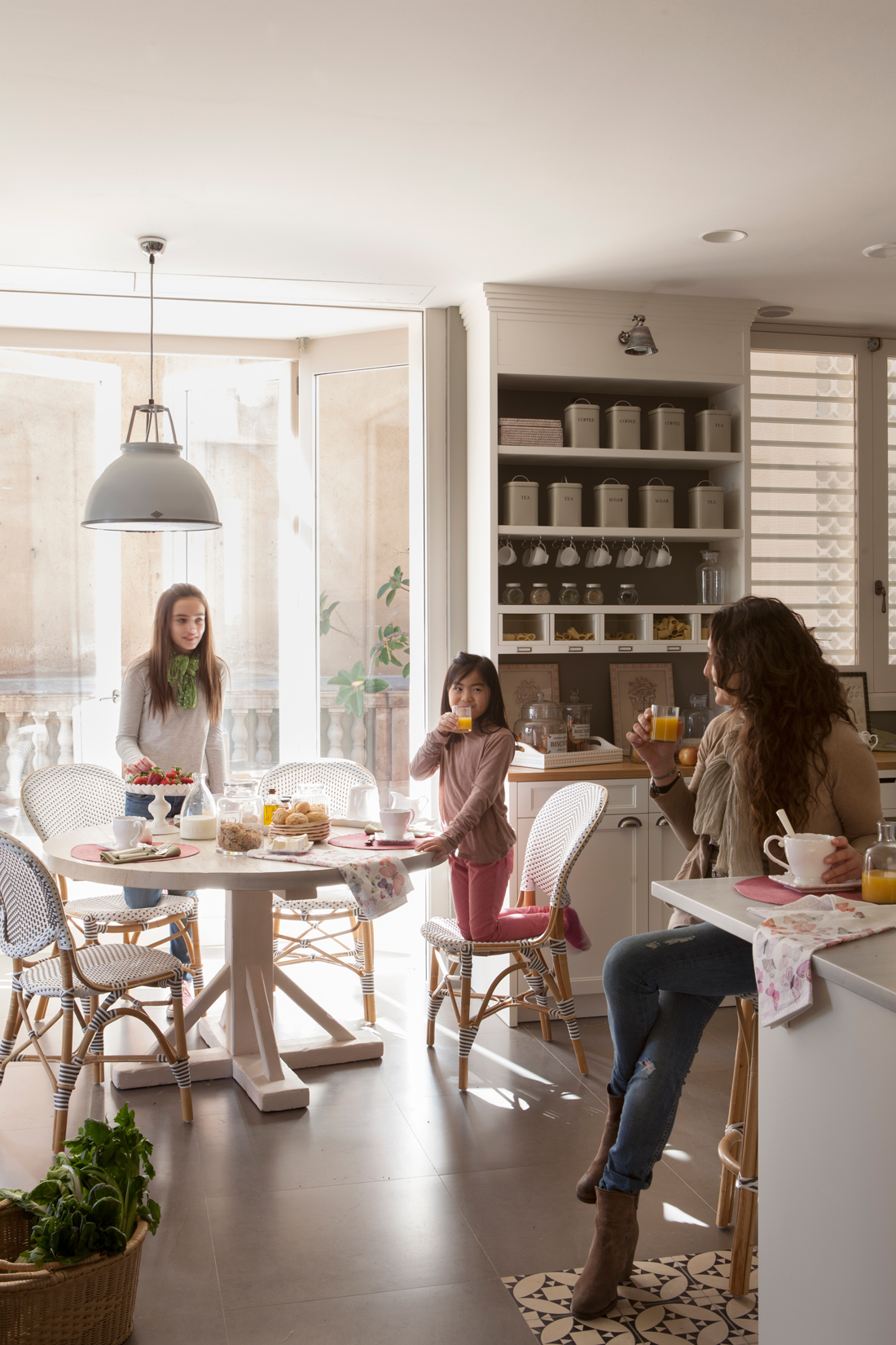 Cocina con office con mesa redonda y mujer y dos niñas