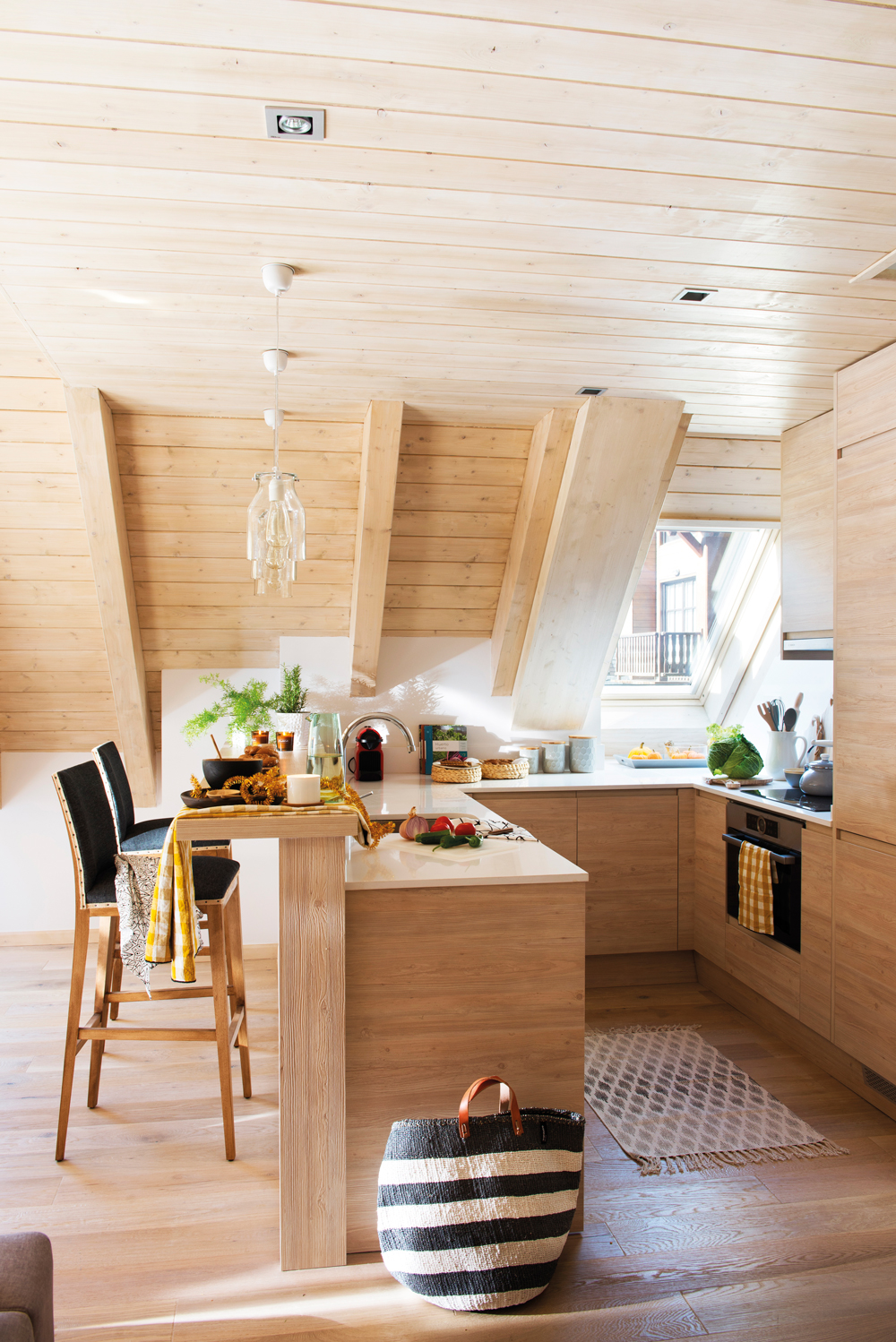 Cocina de madera de casa de montaña con mini barra que hace de office. 