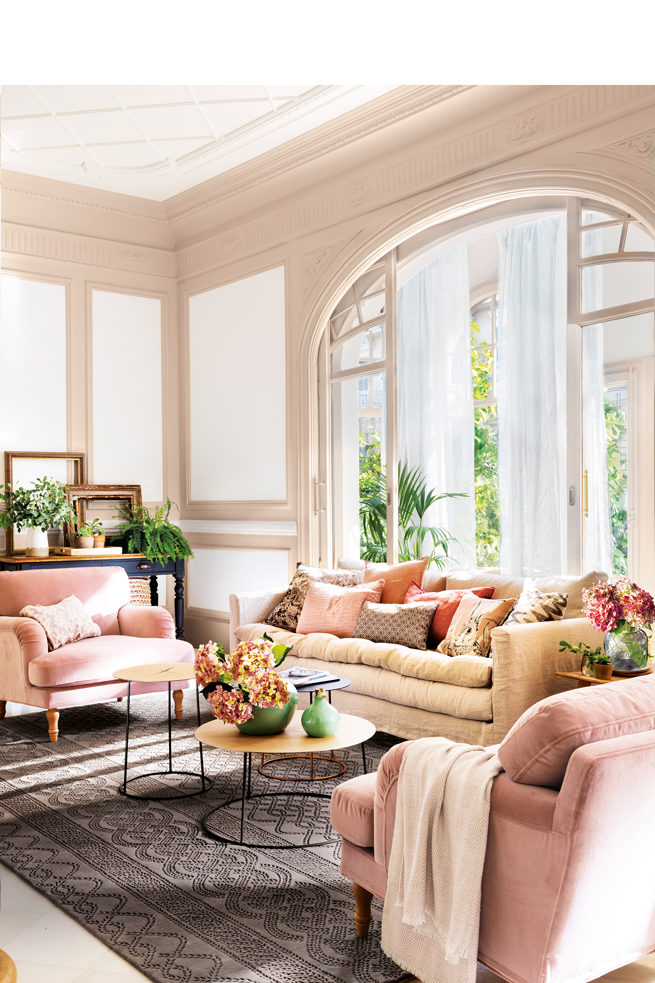 Salón con sofás rosas y techos altos con molduras. 