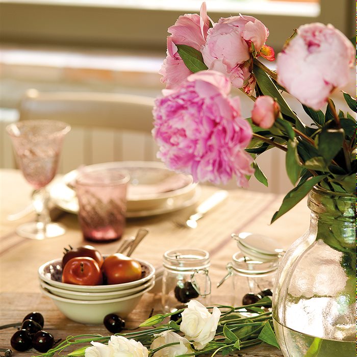 Detalle de jarrón con flores y vajilla sobre la mesa