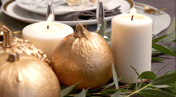 detalle mesa elegante con velas y calabazas doradas