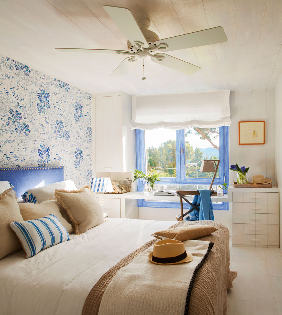 Dormitorio en tonos blancos y azules con textiles en tonos tierra. 