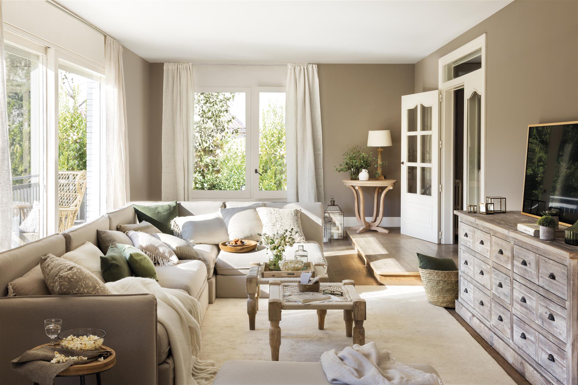 Un salón moderno con un sofá modular en gris claro y cojines blancos, grises y verdes.