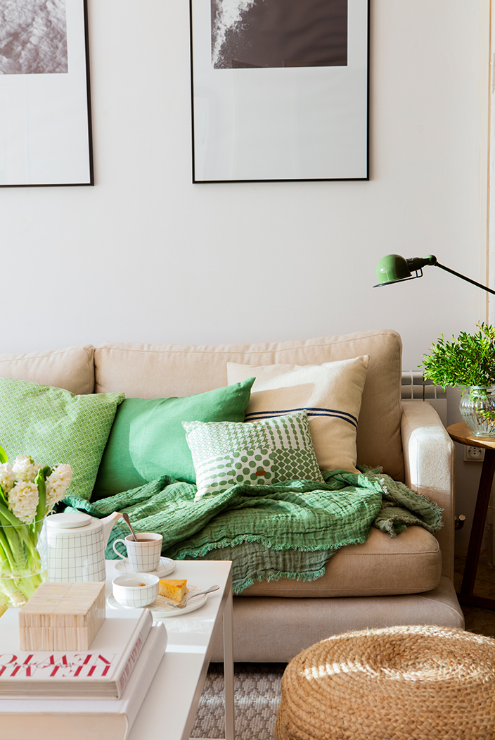 Sofá beige con cojines verdes con diversos estampados. 