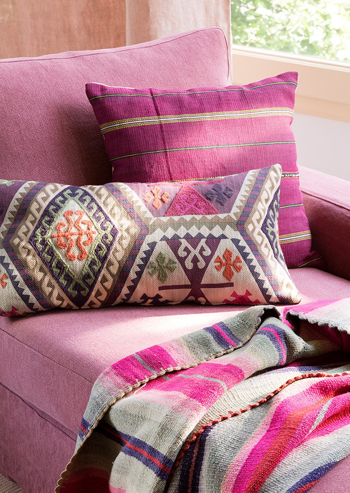 Sofá con cojines de inspiración mexicana en rosa. 