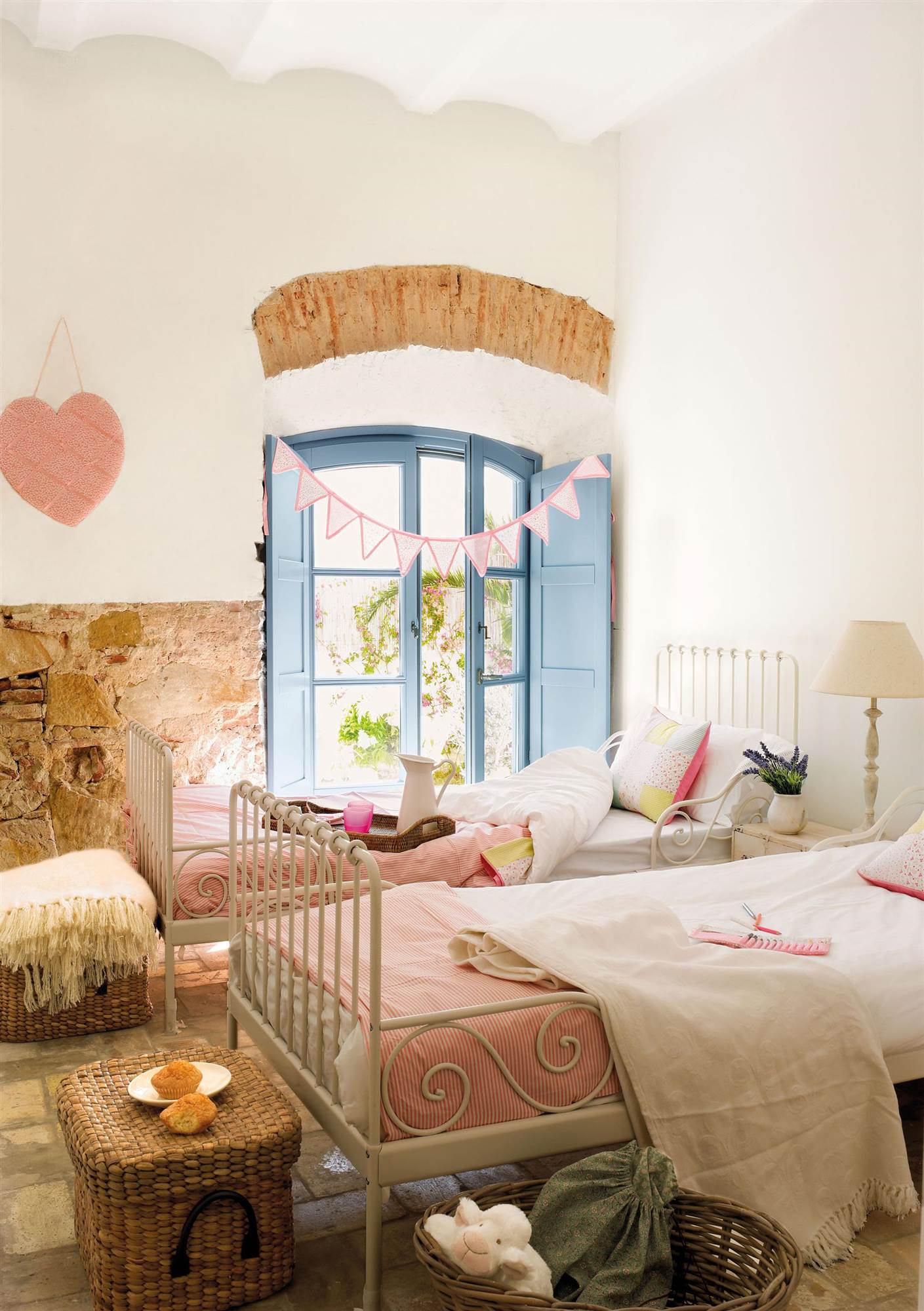 Dormitorio infantil de estilo rústico con camas idénticas, cestos de fibra trenzada y venana azul. 