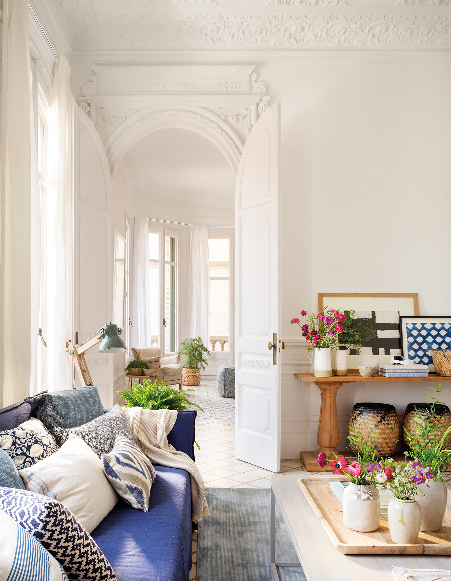 Salón en piso regio con sofá azul y plantas y flores