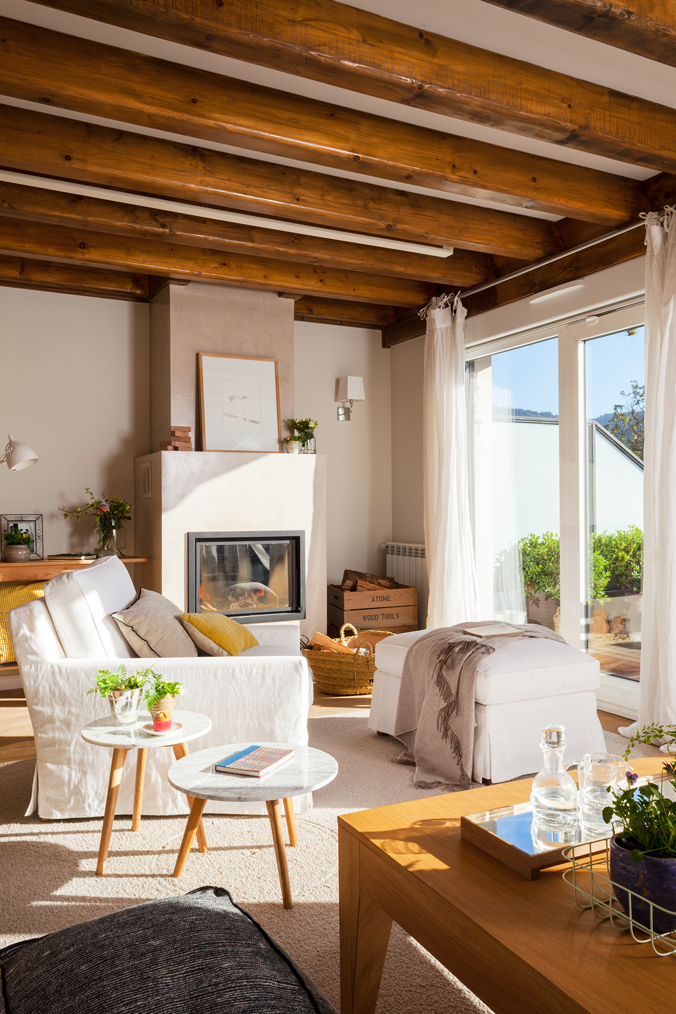 Salón de casa rústica actual con vigas de madera y butaca en blanco.