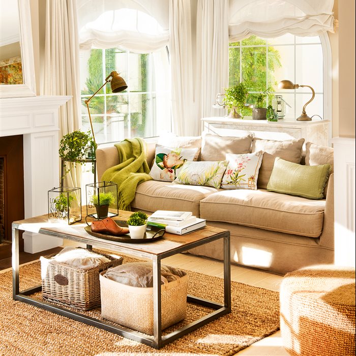 Salón con sofá beige, cojines de tonos verdes, lámparas vintage, mesa de centro en madera y hierro, cortinas y estores blancos y alfombra de fibra natural