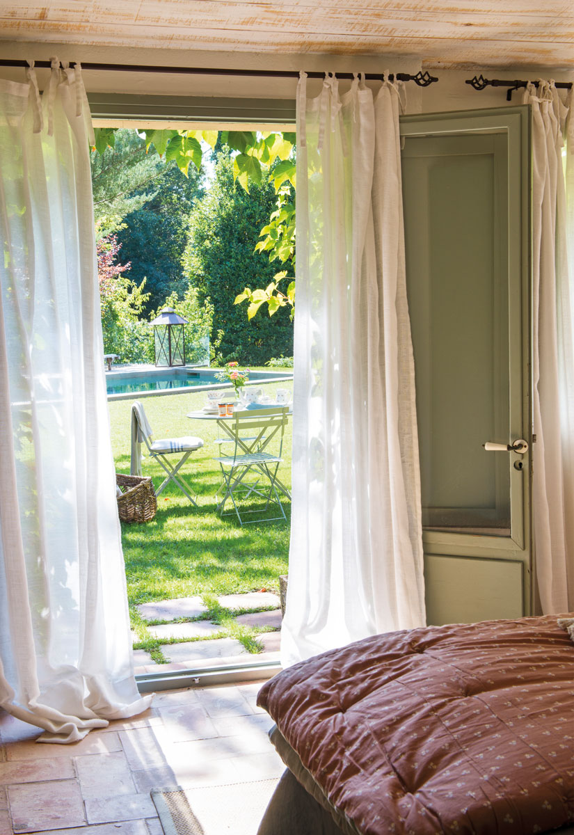 Dormitorio con ventanal que da al jardín
