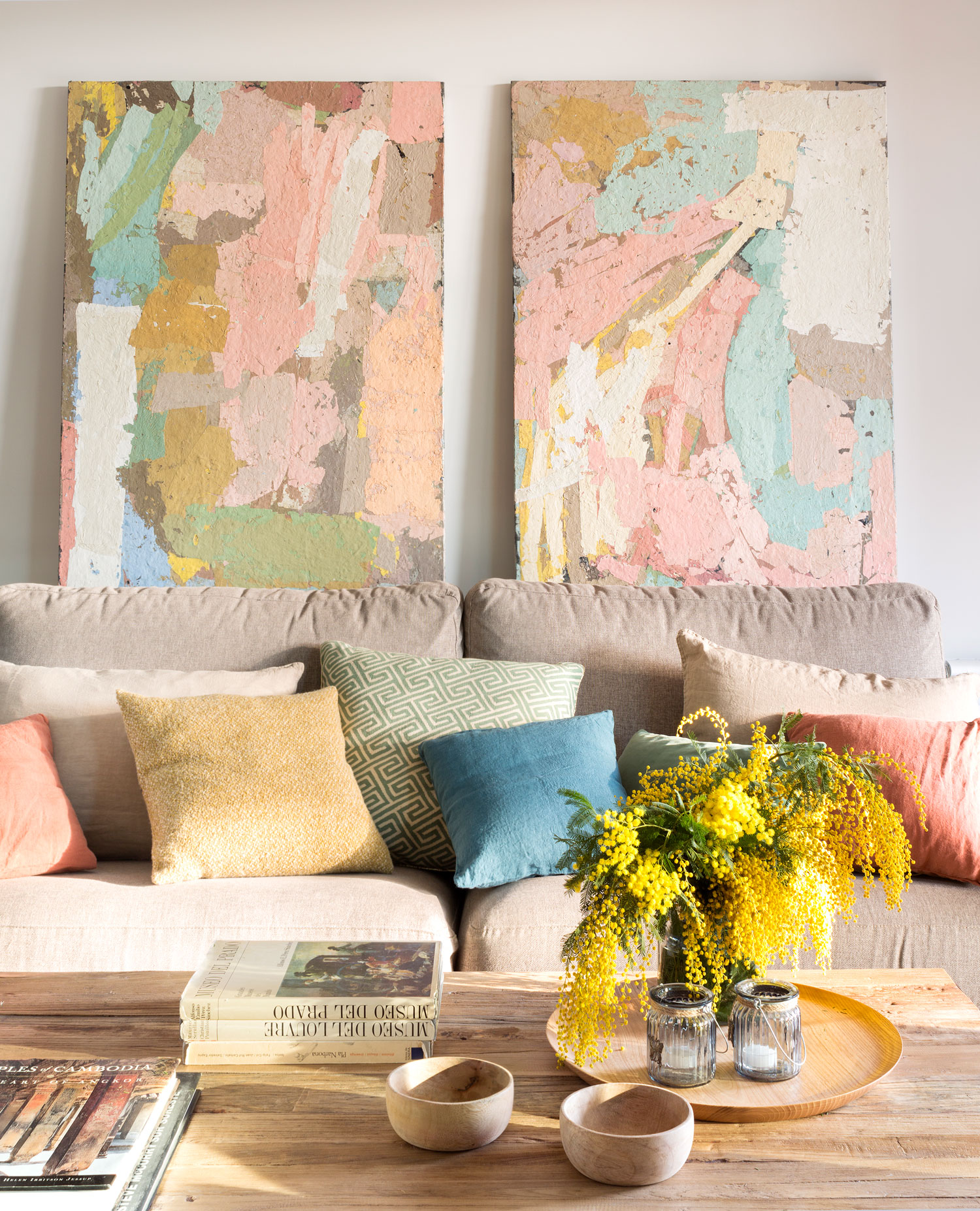 Salón con sofá beige, cuadros abstractos y mesa de centro de madera