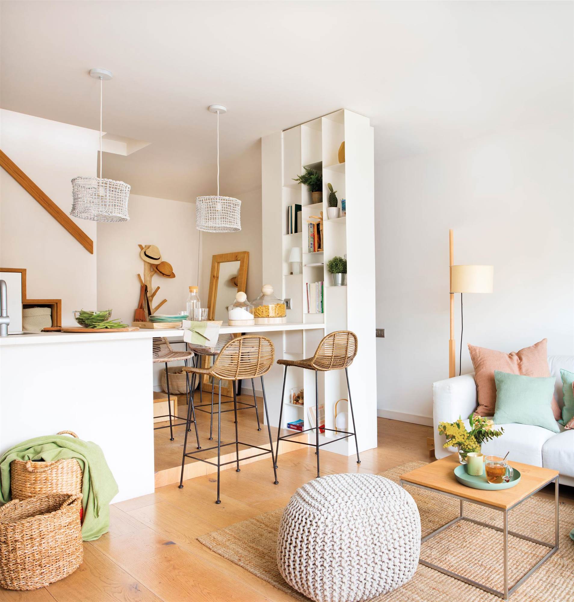 Salón abierto a la cocina con sofá neutro y detalles de fibras y madera