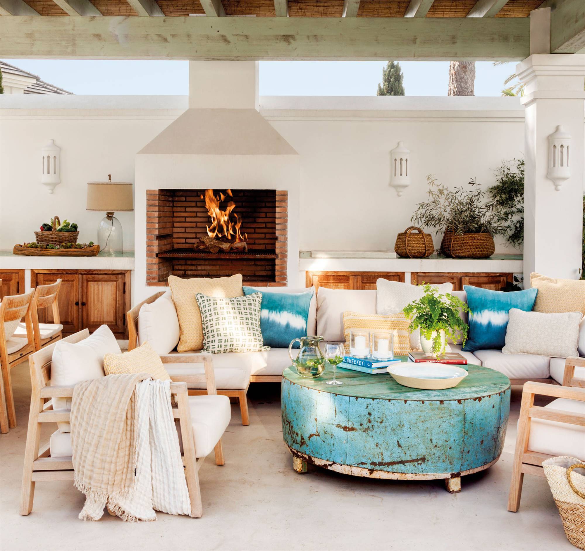 Porche con sofás y butacas de madera de teca y mesa de centro azul turquesa. 