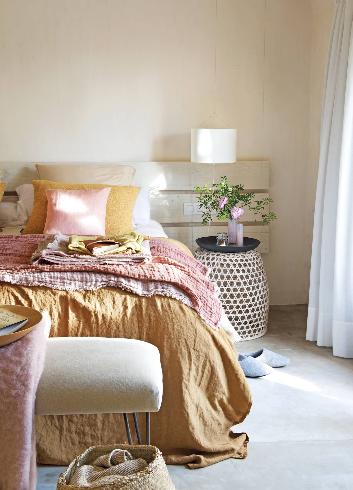 Dormitorio moderno con mesa de noche original y telas de la ropa de cama luminosas en amarillos, mostazas y naranjas. 