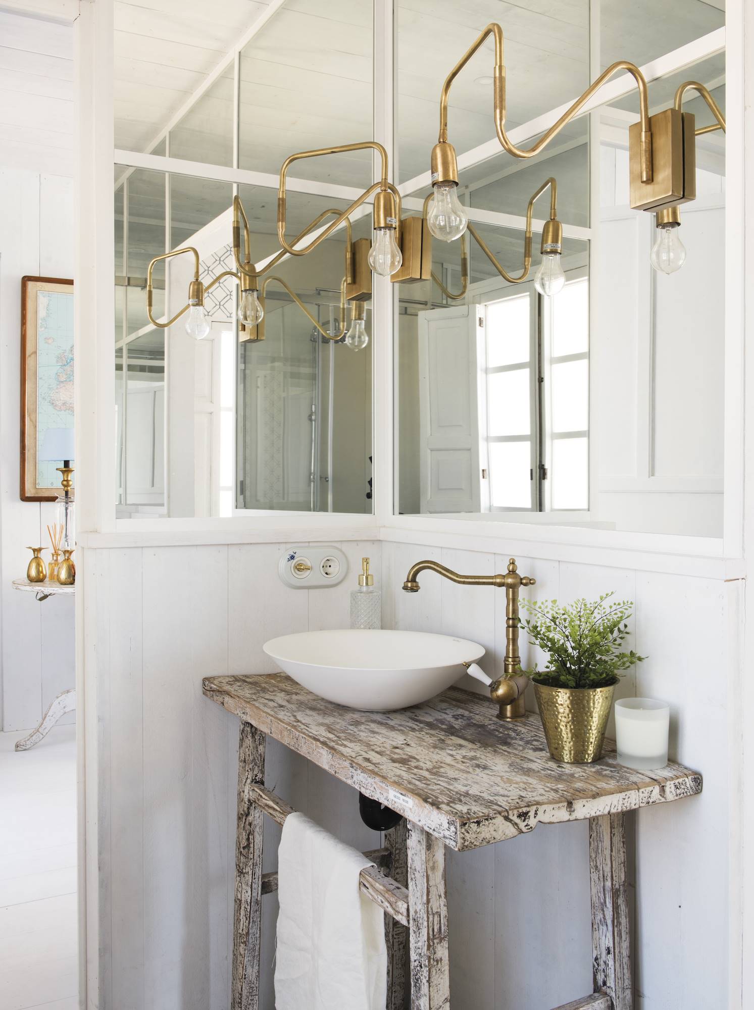 Baño con mesa antigua vintage, grifería dorada y dos espejos. 
