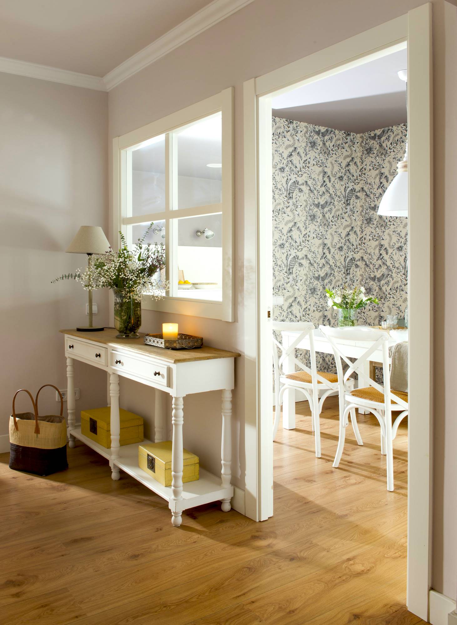 Recibidor pequeño con papel pintado, muebles blancos y detalles en amarillo.