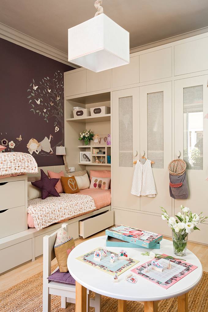 Un dormitorio infantil con la cama integrada al mueble armario, con cajones, puertas y baldas.