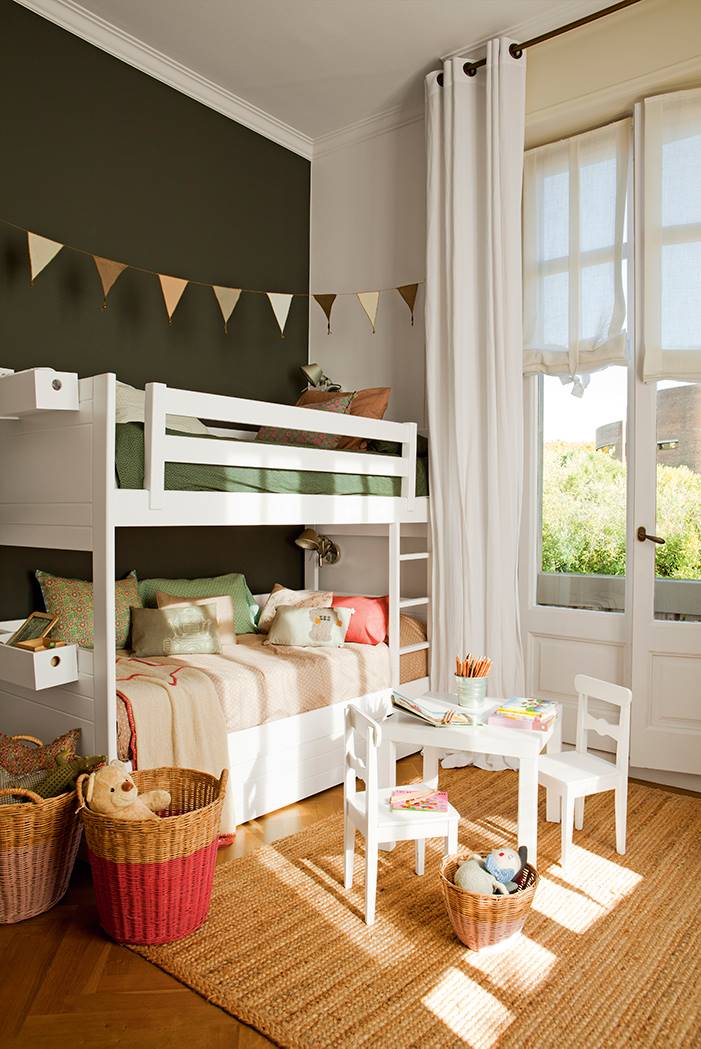 Dormitorio infantil con litera blanca y pared negra con alfombra de fibras vegetales.
