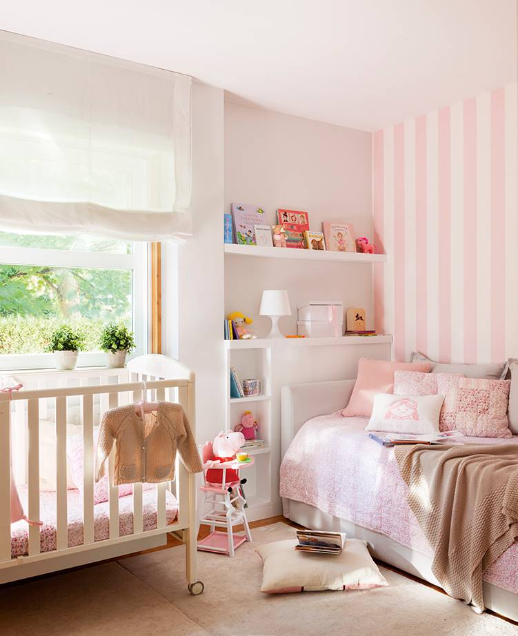 Una habitación infantil con el rosa como color protagonista y una cuna.