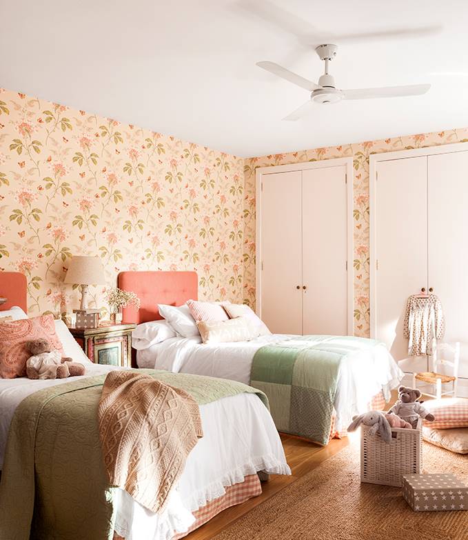 Una habitación infantil con dos camas con los cabeceros color coral.