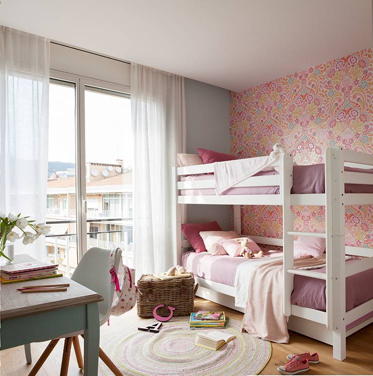 Una habitación infantil con una litera y papel pintado en una de las paredes. 