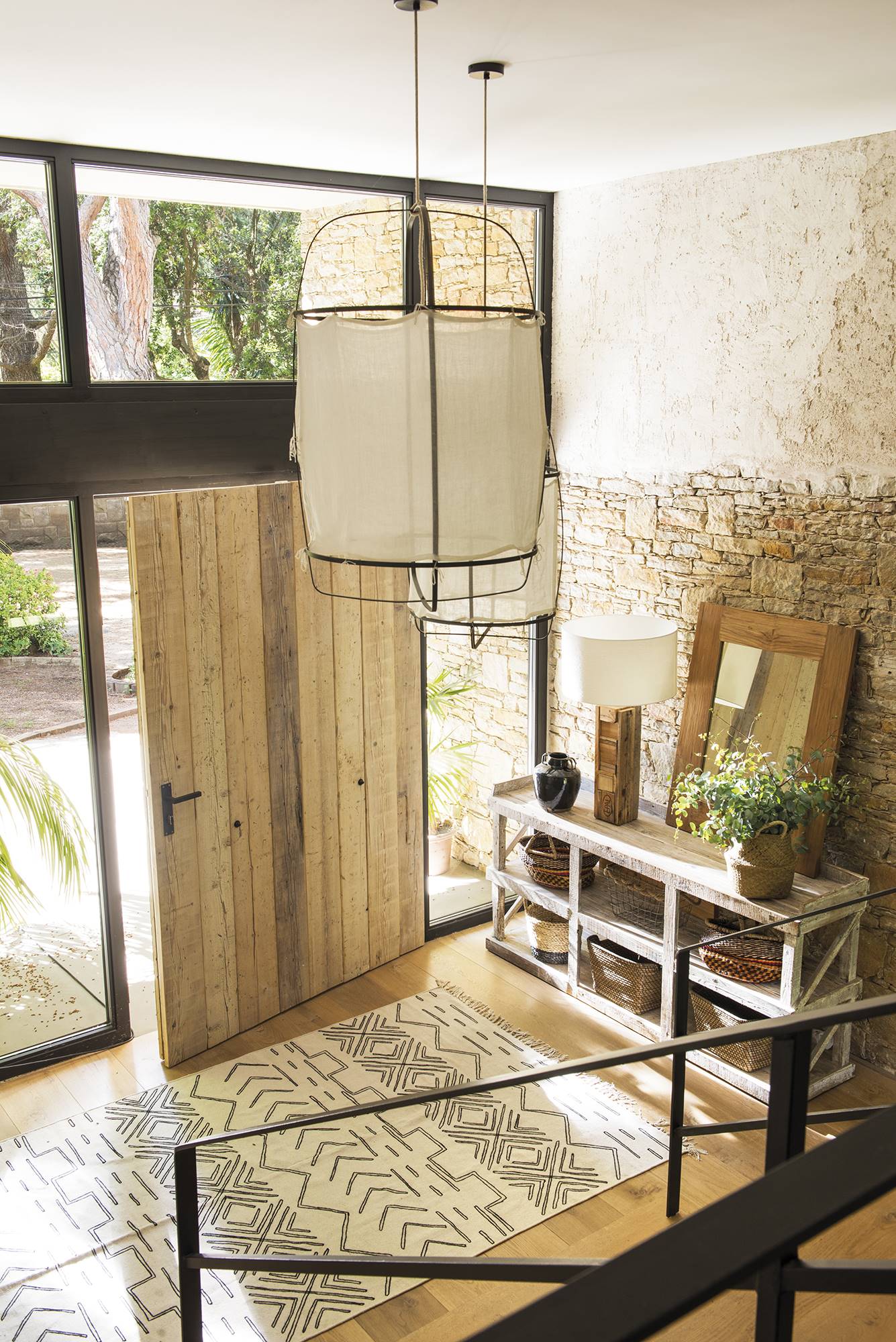 Recibidor rústico moderno con pared de cristal y puerta de madera. 